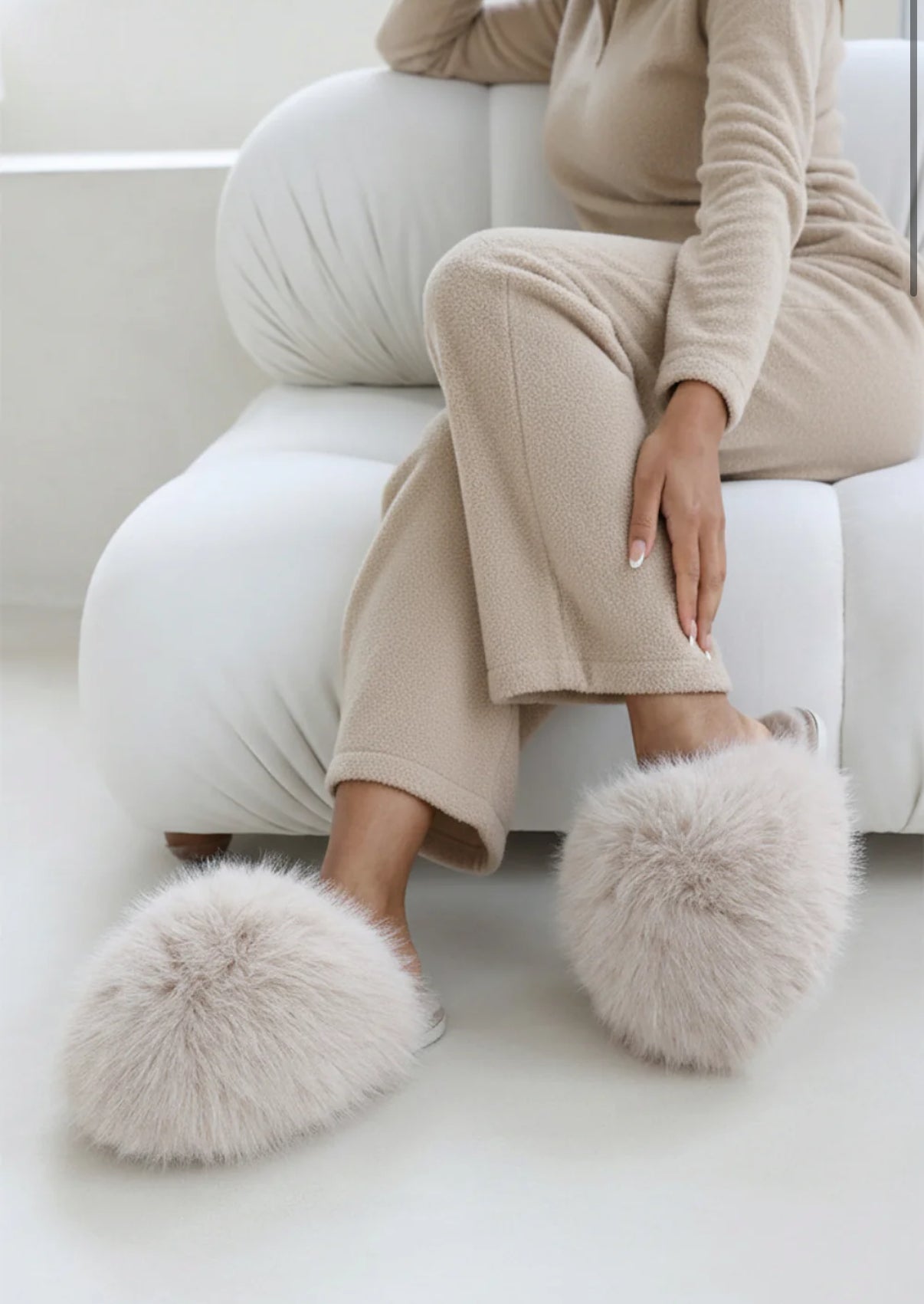 Woman sat down wearing Beige Extreme Oversized Faux Fur Fluffy Slippers