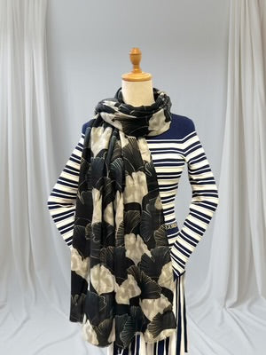 Mannequin wearing a striped sweater and black and white patterned scarf against a white curtain background
