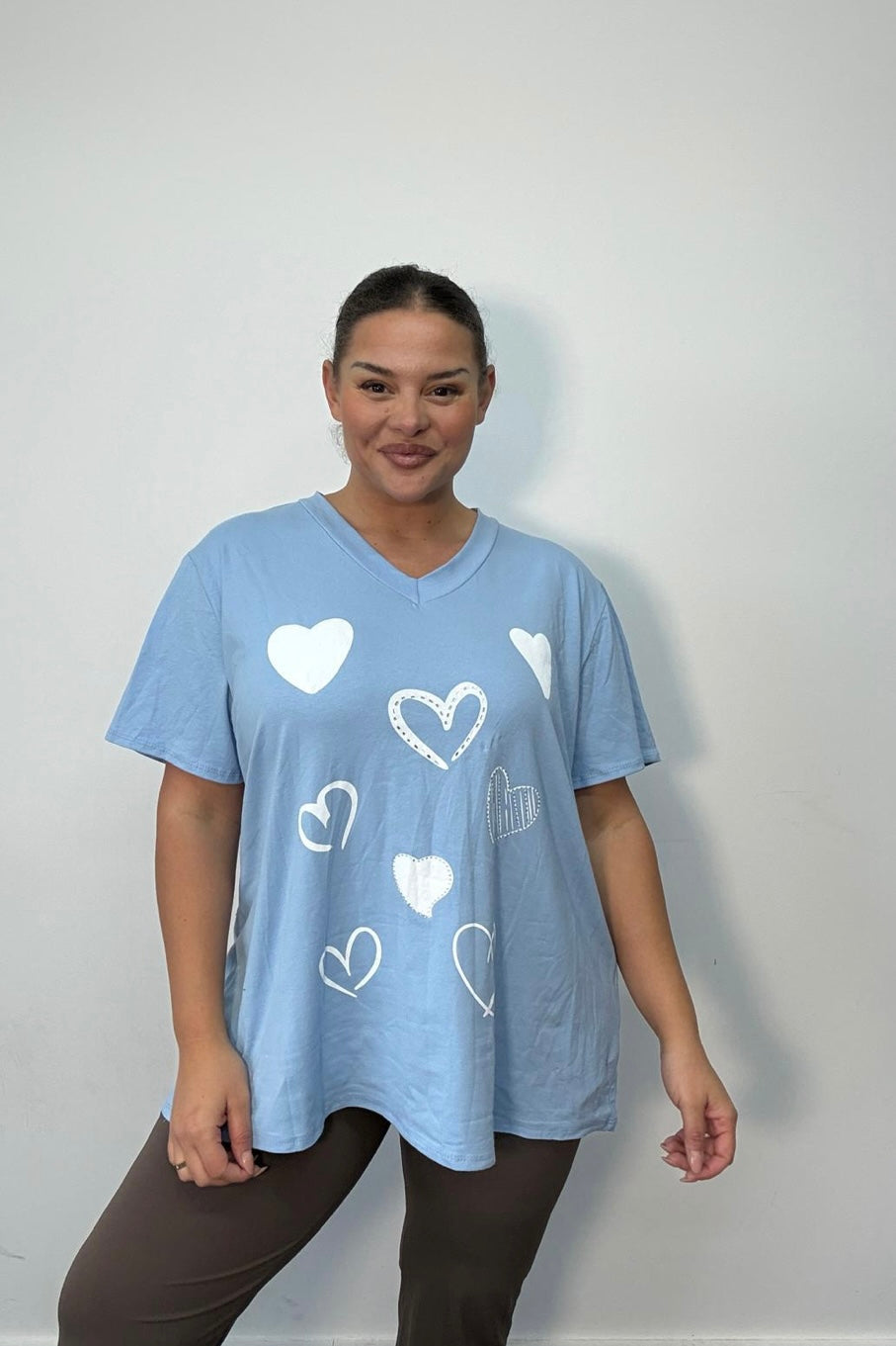Woman wearing a blue Plus Size All-Over Heart Print Oversized T-Shirt on a plain background