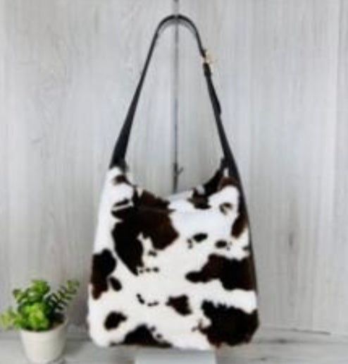 Brown and white cow print handbag on a light gray background
