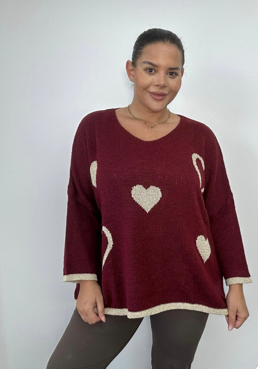 Woman wearing a burgundy sweater with heart patterns on a plain background
