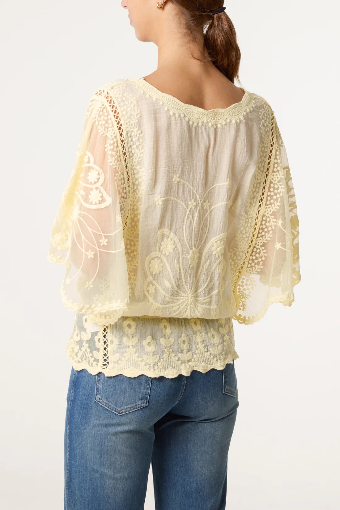 Rear view of Woman wearing a Lemon Yellow Floral Lace Butterfly Sleeve Blouse Top and blue jeans on a white background