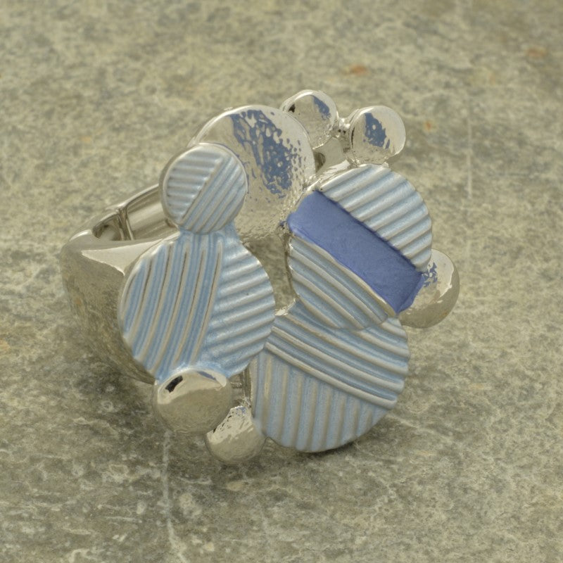 Silver ring with blue and silver patterned stones on a textured surface