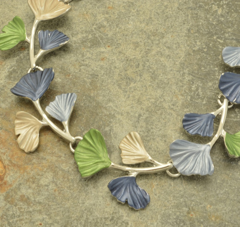 Miss Milly Multicolour Ginkgo Necklace with leaf-like pendants on a textured surface