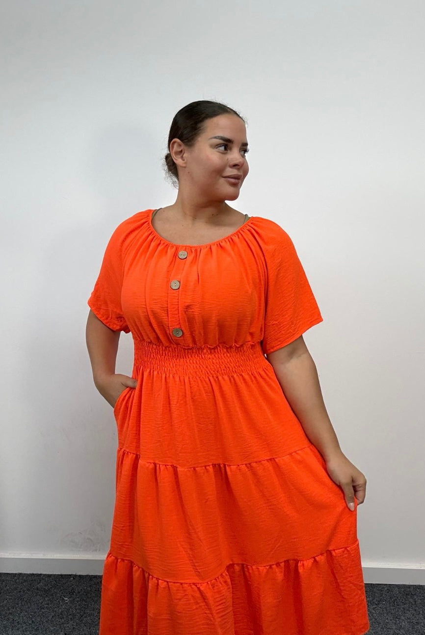 Woman wearing a Plus Size Orange Button Detail Tiered Midi Dress with Pockets with a plain background