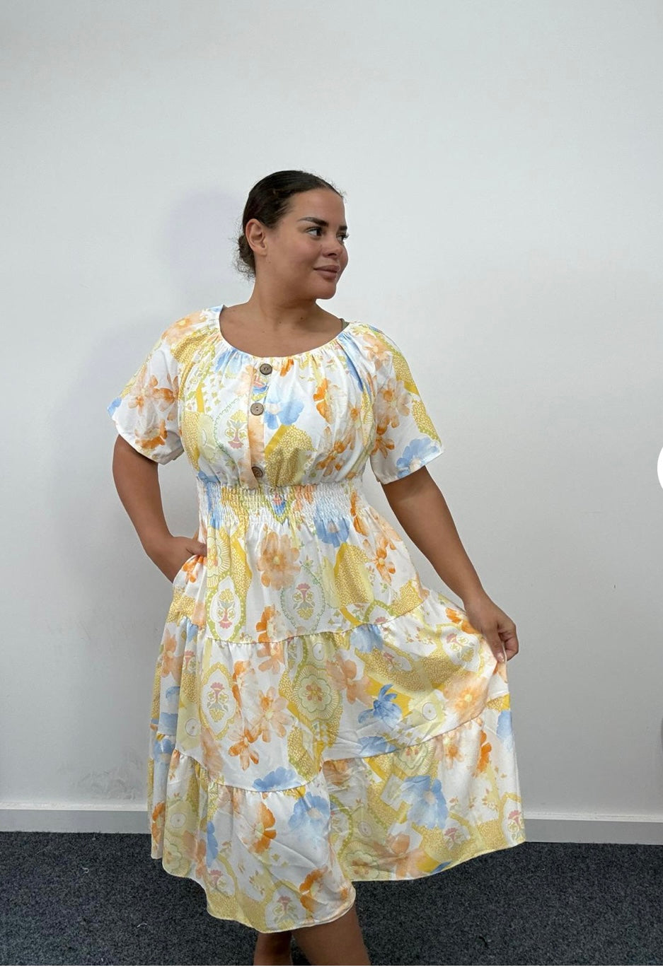 Woman wearing a Plus Size Yellow Floral Print Tiered Shirred Waist Midi Dress with Pockets against a plain background