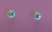 Pair of round aqua gemstone earrings on a pink background