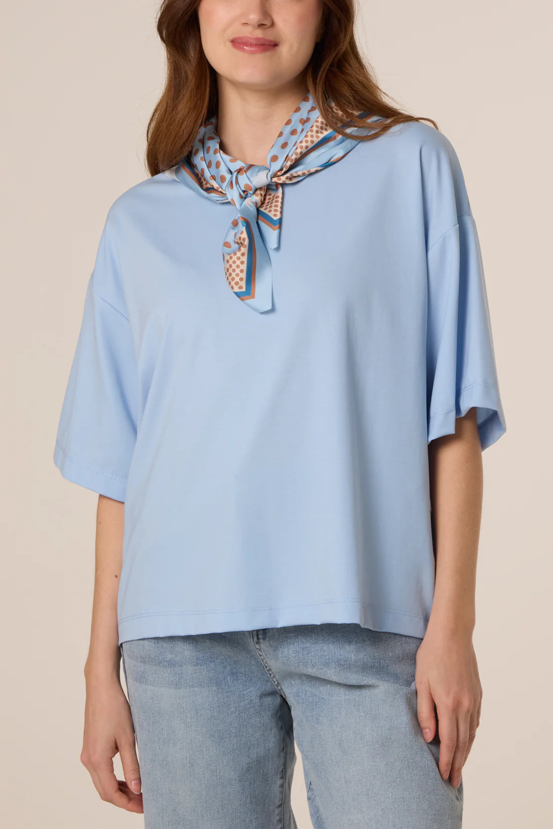 Woman wearing a Baby Blue Back Polka Dot Scarf Short Sleeve T-Shirt against a beige background