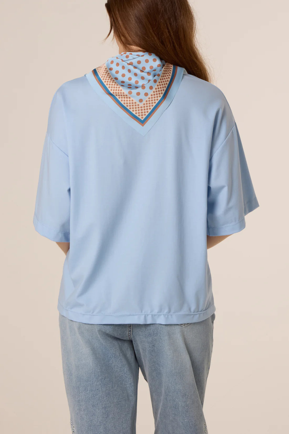 Person wearing a Baby Blue Back Polka Dot Scarf Short Sleeve T-Shirt against a beige background