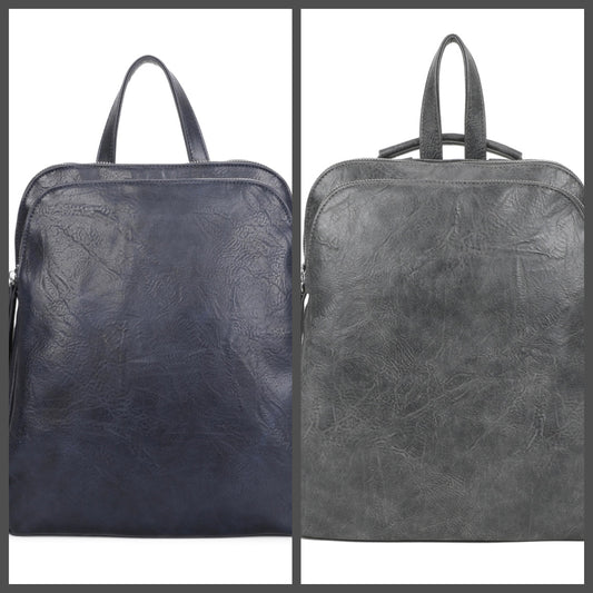 Two backpacks shown side by side against a white background, each framed by a dark gray border. The left backpack is dark navy blue with a textured faux-leather finish, and the right backpack is dark gray with the same texture.