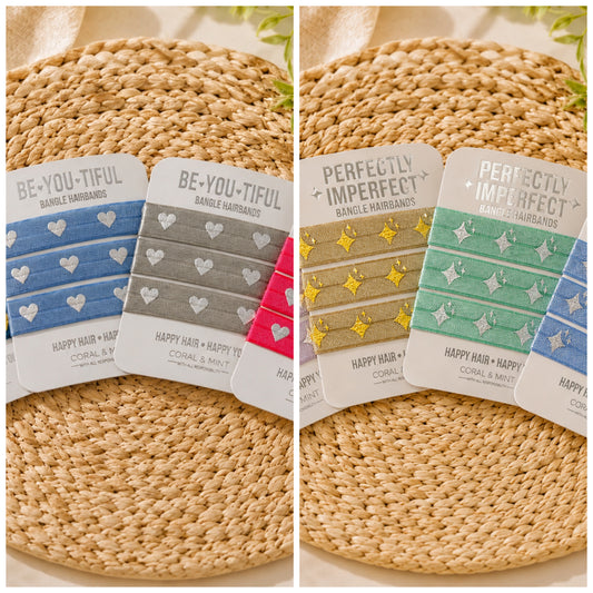 Two side-by-side product displays showing packaged single hairbands laid on woven round mats. The left set reads 'BE-YOU-TIFUL' and shows blue, gray, and pink hairbands with white heart patterns.