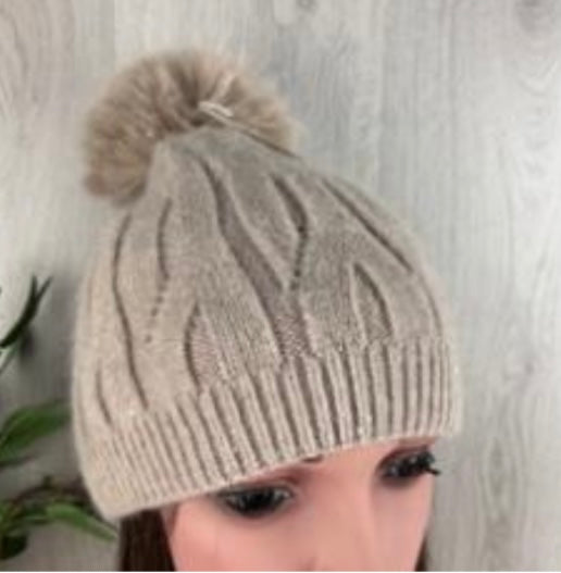 Beige knit beanie with pom-pom on a neutral background