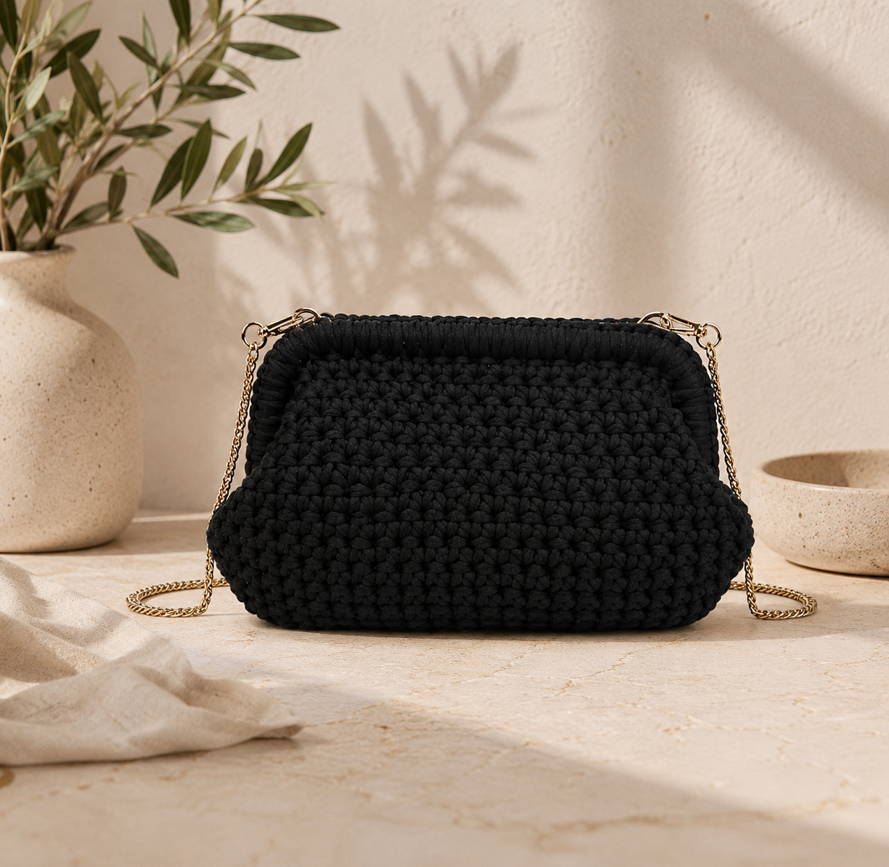 Black woven handbag with gold chain strap on a neutral background