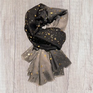 Black and gray scarf with gold polka dots on a wooden surface