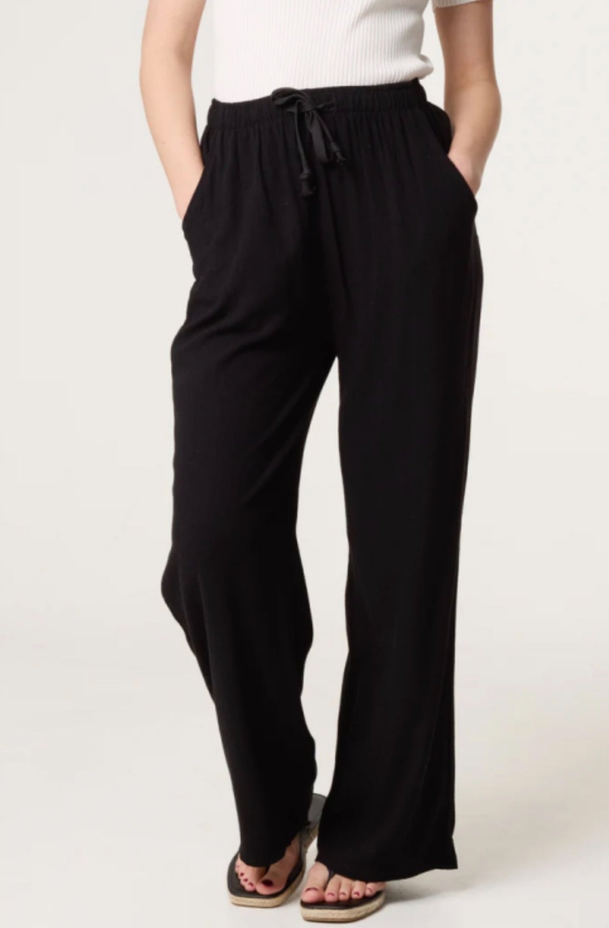 Person wearing Black Linen Blend Drawstring Pocket Trousers with a white top on a light background