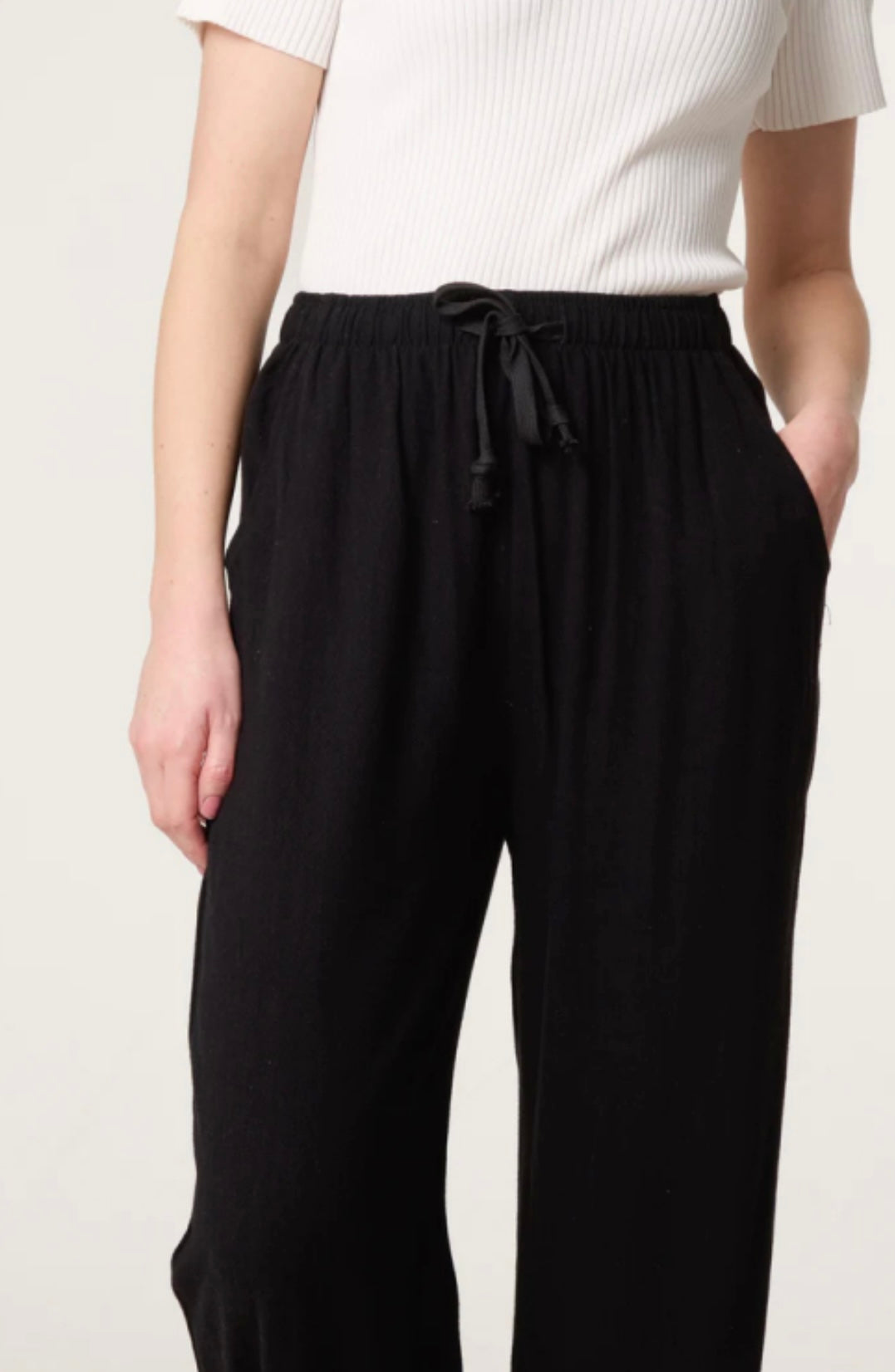 Person wearing Black Linen Blend Drawstring Pocket Trousers with a white top on a plain background