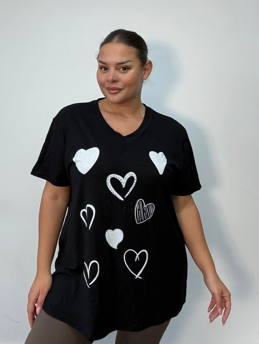 Woman wearing a Black Plus Size All-Over Heart Print Oversized T-Shirt on a plain background