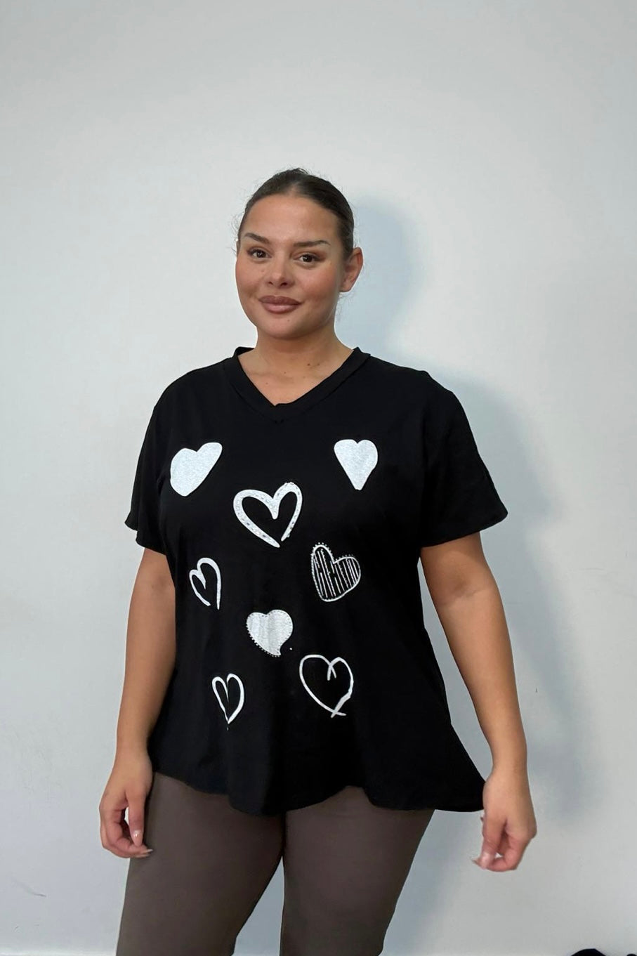 Woman wearing a Black Plus Size All-Over Heart Print Oversized T-Shirt against a plain background
