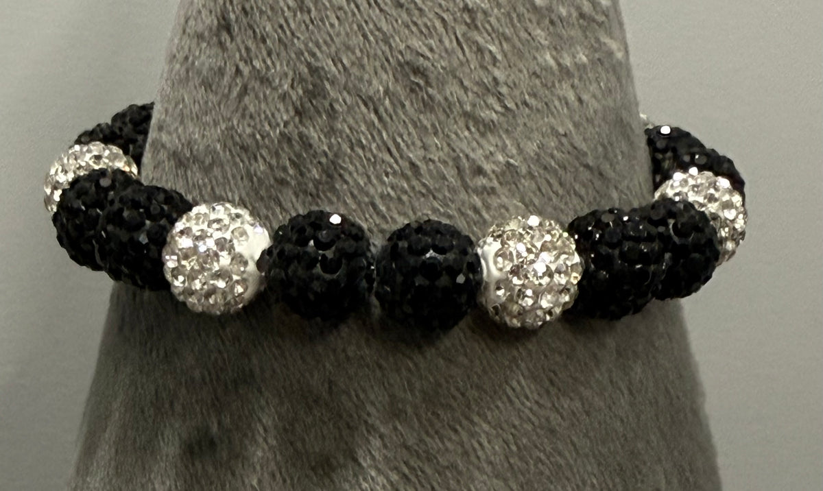 A beaded stretch bracelet displayed on a gray textured cone stand. The bracelet features alternating black textured beads and silver faceted crystal dome beads.