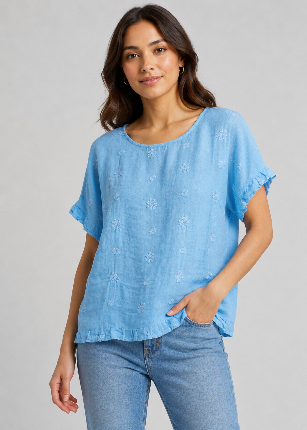 Woman wearing a blue blouse with ruffled sleeves against a gray background