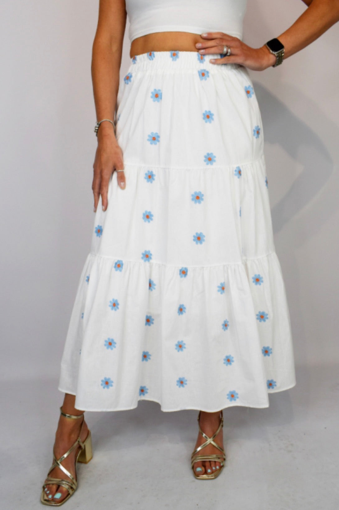 White skirt with blue floral patterns worn by a person on a plain background