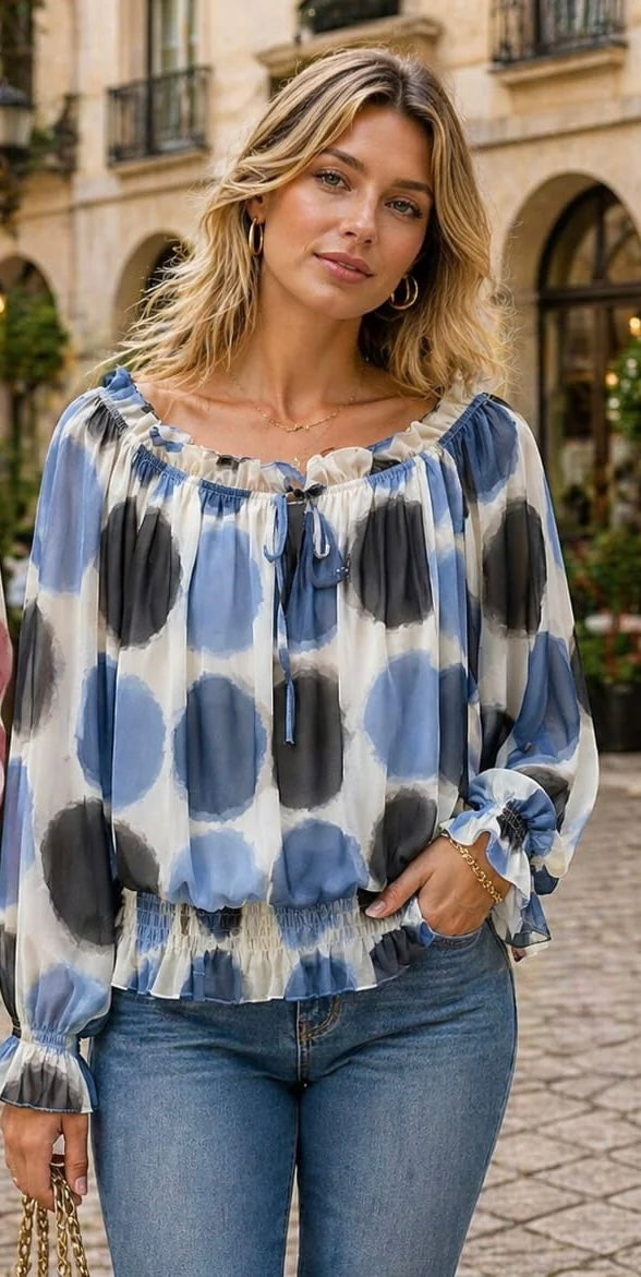 Woman wearing a blue and black polka dot blouse with jeans on a street.