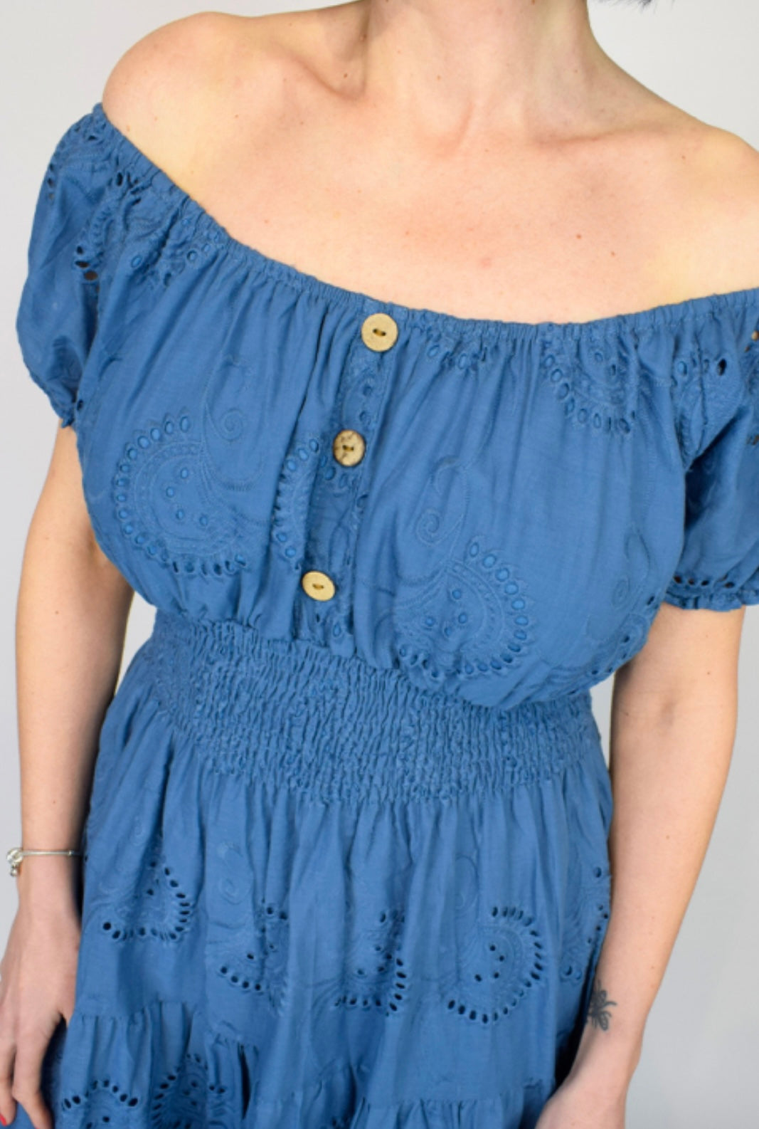 Off-shoulder Blue Embroidery Anglaise Bardot Midi Dress with button details on a plain background