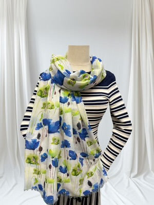 Mannequin wearing a striped sweater with a floral scarf draped over it against a white curtain background