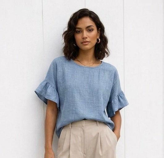 Woman wearing a blue top with ruffled sleeves against a white background