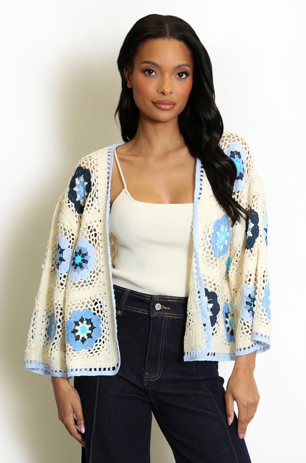 Woman wearing a Blue and cream Open Floral Crochet Cardigan on a plain background