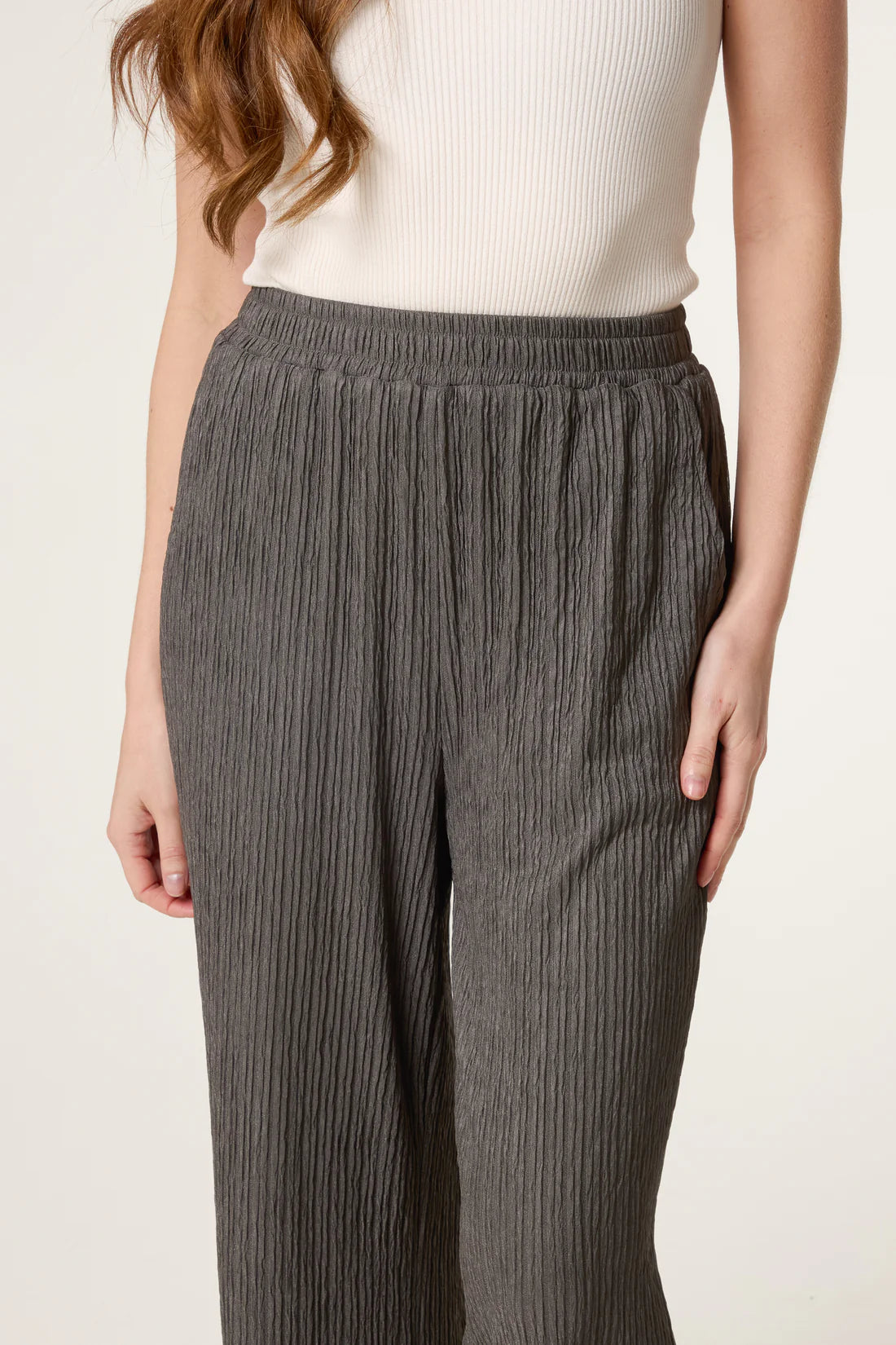 Person wearing Dark Khaki Elastic Waist Crinkle Trousers and a white top on a plain background