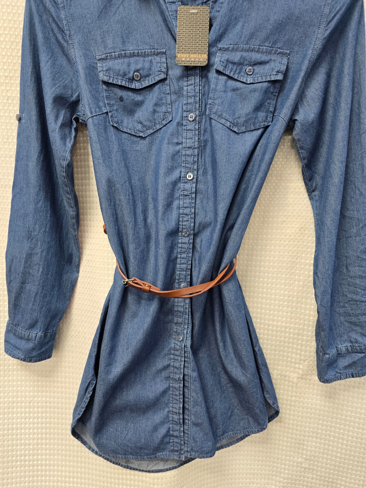 Blue denim shirt Dress with a belt on a beige textured surface