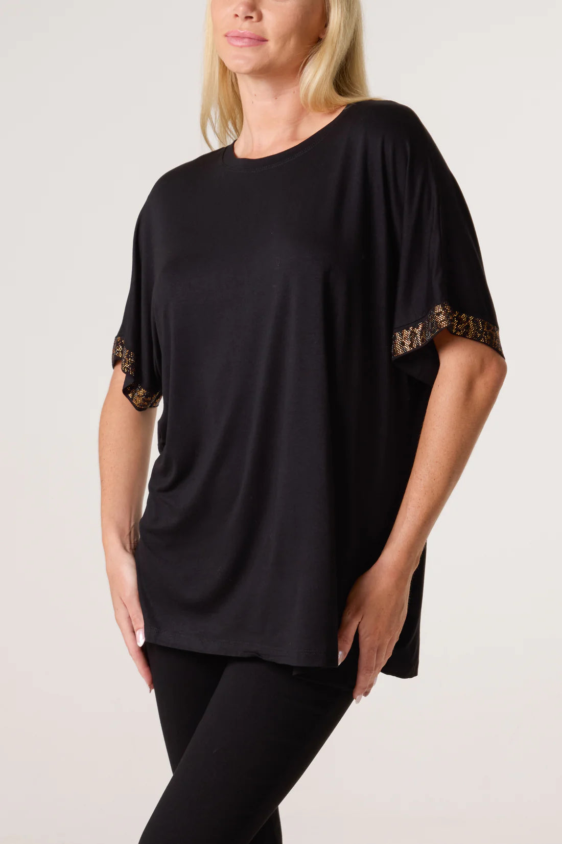 Woman wearing a black top with diamante sleeves on a plain backgroundnt 