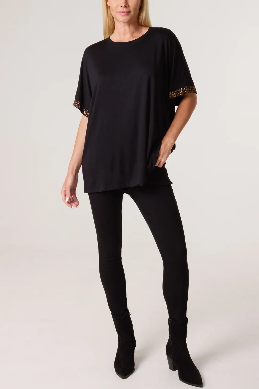 Woman wearing a black oversized t-shirt with diamante sleeves on a white background