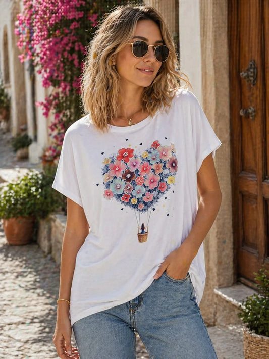 Woman wearing a white t-shirt with a colorful flower hot air balloon design, standing outdoors.