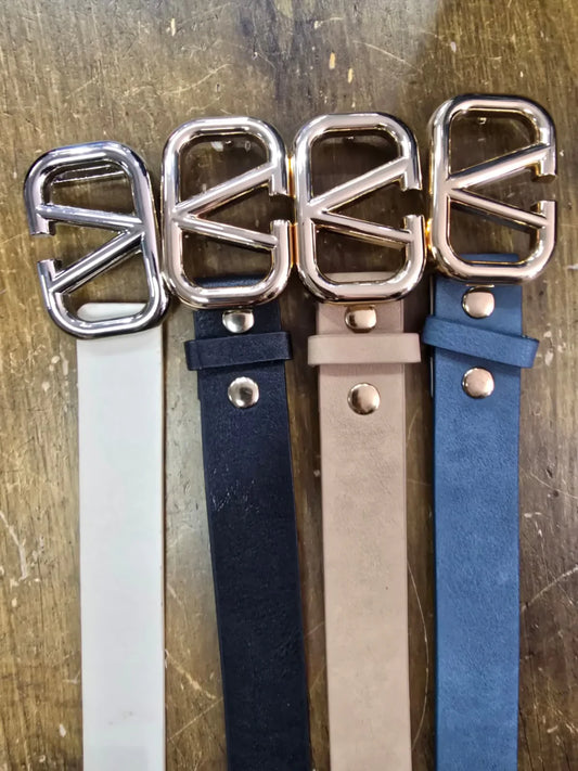 Four belts with gold buckles on a wooden surface