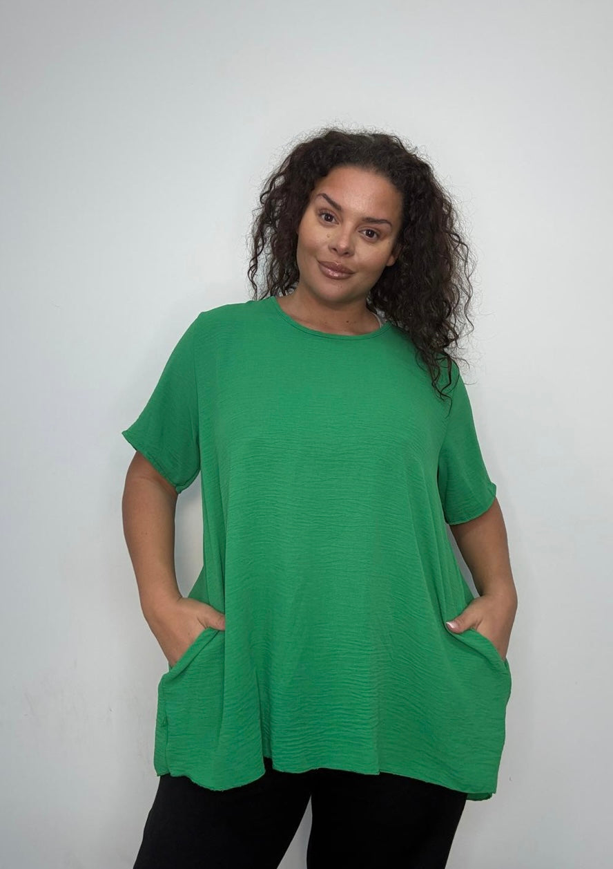 Woman wearing a Green Plus Size Pleated Back Oversized T-Shirt with Pockets against a white background