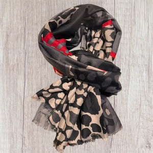 Leopard print scarf with black and red accents on a wooden surface