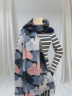 Person wearing a patterned scarf over a striped sweater against a white curtain background
