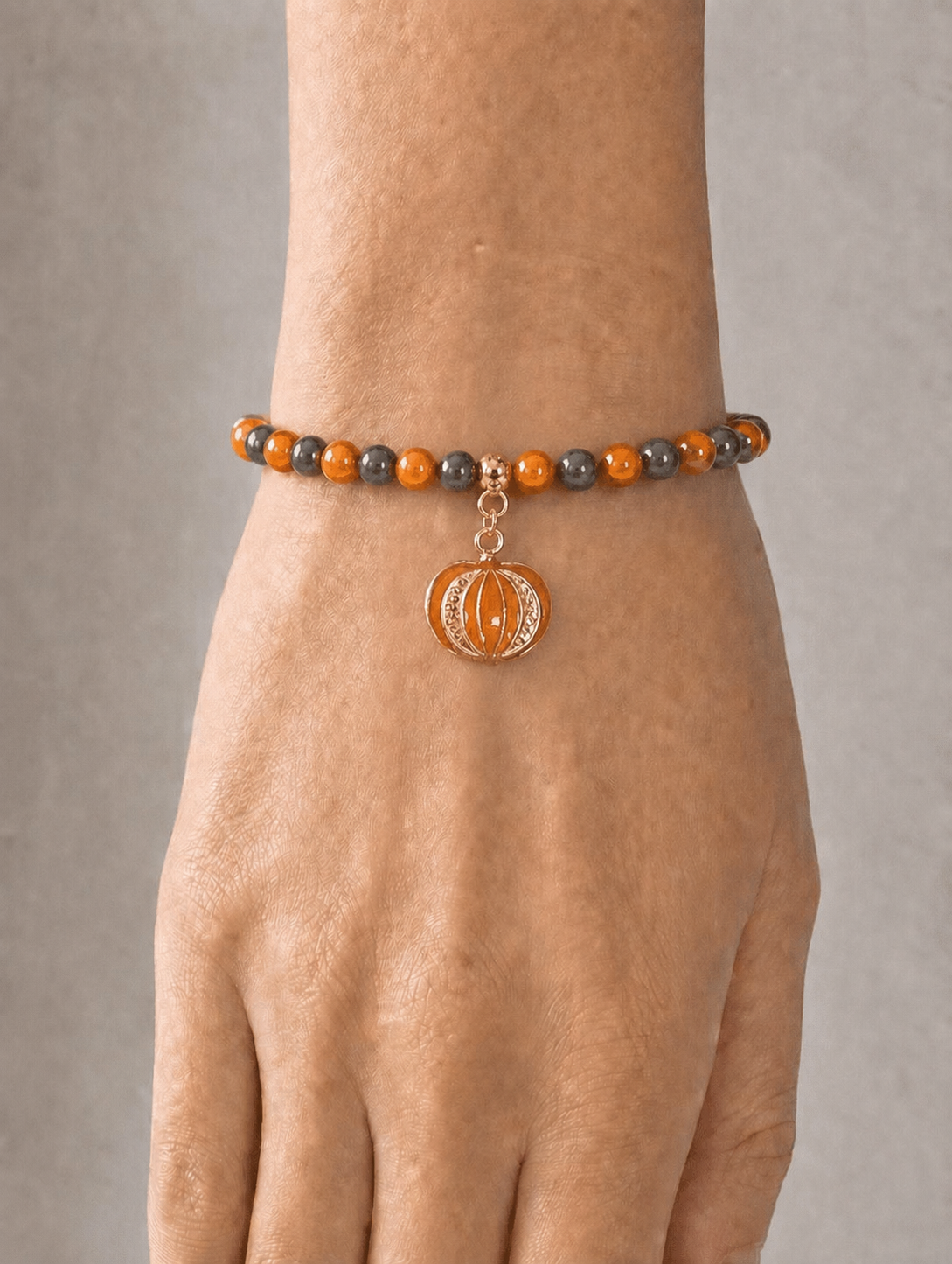 Stretch bracelet with black and orange beads and pumpkin charm on a wrist 