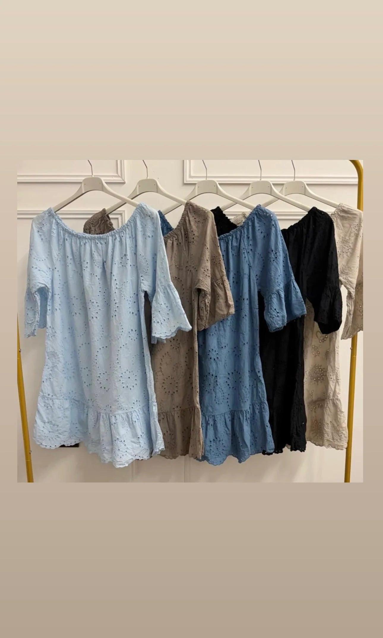 Collection of dresses on hangers against a neutral wall