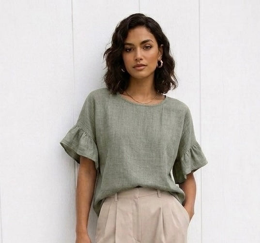 Woman wearing a green ruffled blouse against a white background