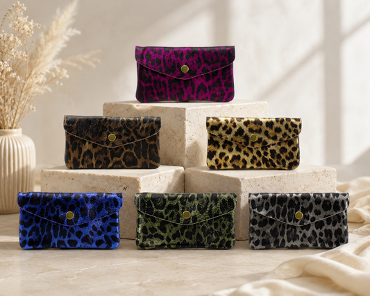 Set of leopard print leather purses on a decorative surface with a neutral background