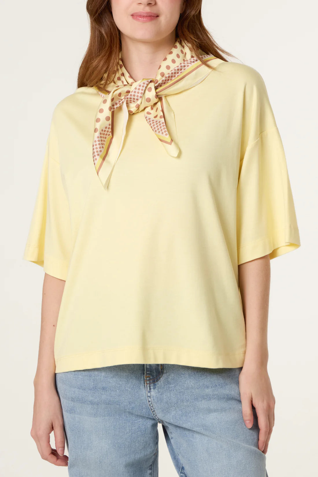 Woman wearing a Lemon Yellow Back Polka Dot Scarf Short Sleeve T-Shirt and blue jeans on a white background
