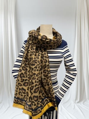 Mannequin wearing a striped sweater with a leopard print scarf against a white curtain background