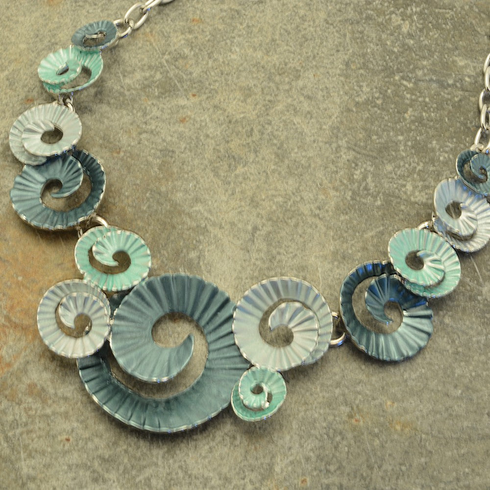Miss Milly Green Ammonite Necklace on a textured surface