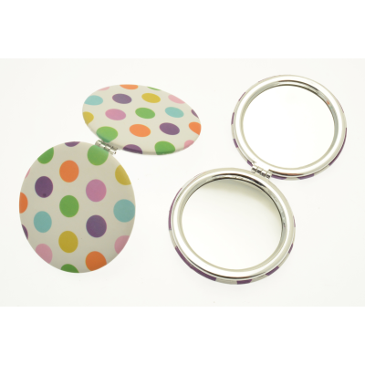 Polka dot compact mirror on a white background