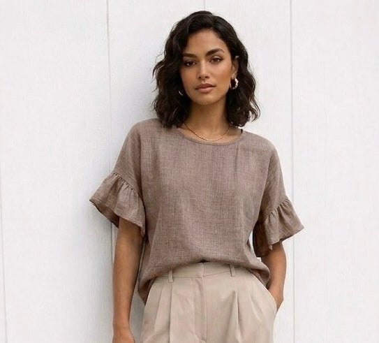Woman wearing a brown ruffled blouse against a white background