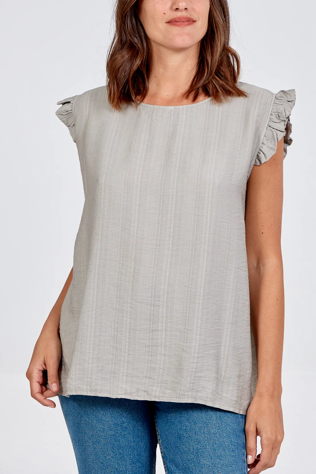 Woman wearing a mocha top with ruffled sleeves on a white background