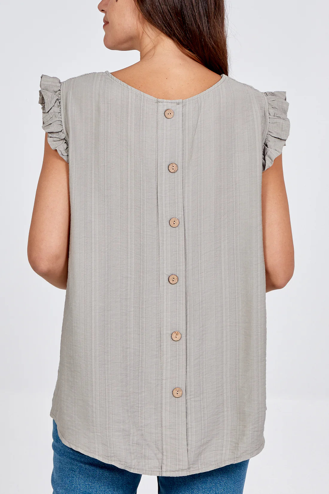 Woman wearing a mocha sleeveless button-up top with ruffled shoulders on a white background